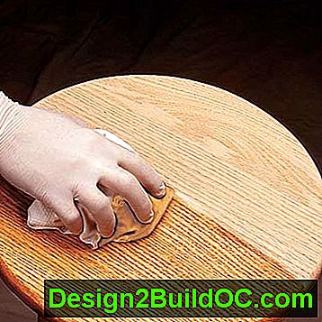 een latex-handschoen veegt een met polyurethaan gedrenkte doek af op een tafelblad