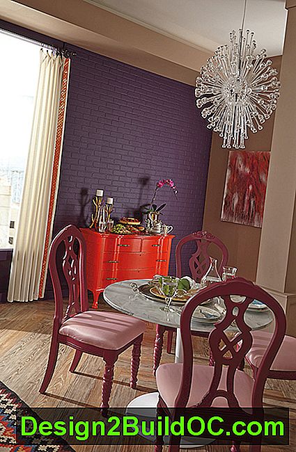 spiseplads med farverige møbler, herunder rød armoire mod mursten malet mørke lilla
