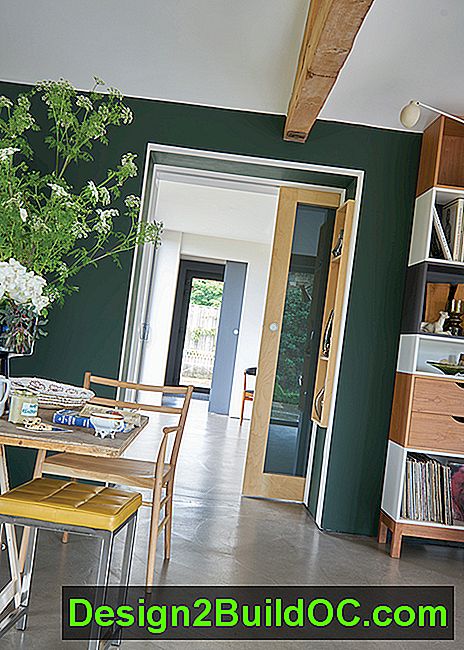 spiseplads med moderne møbler, betongulv og vægmalet mørkegrøn