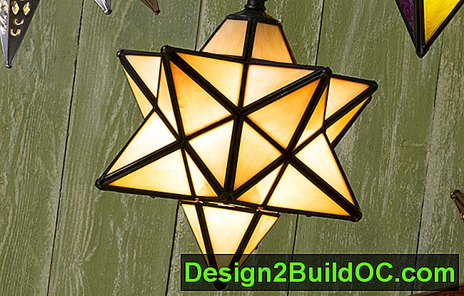 una lampada a sospensione a forma di stella moraviana in vetro opalescente a 12 punti appesa a un muro verde con stecche di legno