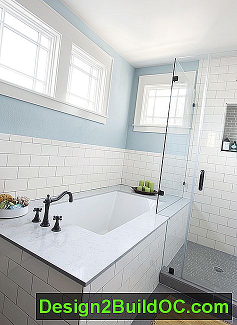 master badeværelse med hvide subway flise surround og rammeløse glas brusebad og et stort badekar
